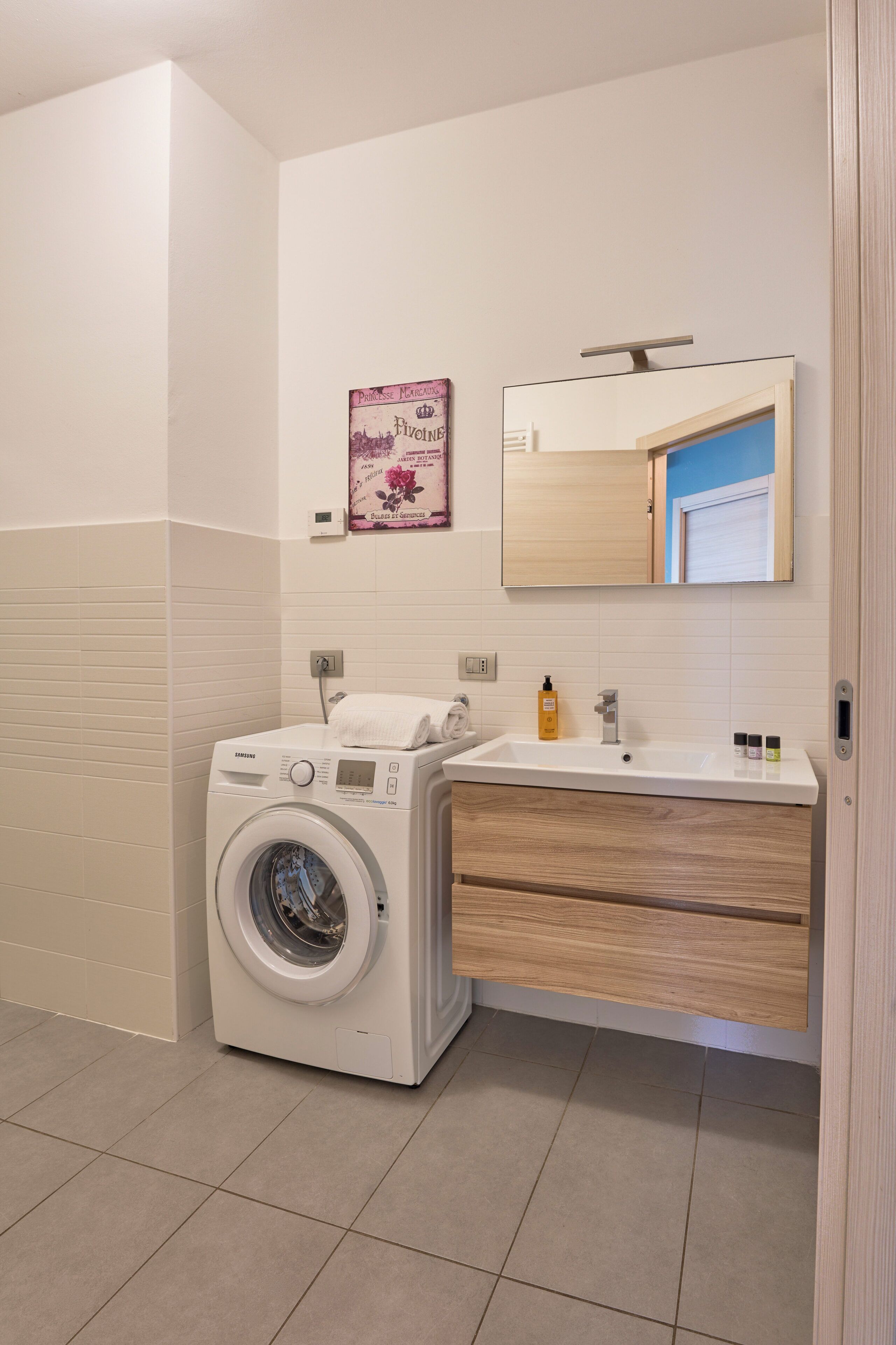 A modern bathroom with a washing machine, a sink, and a mirror.
