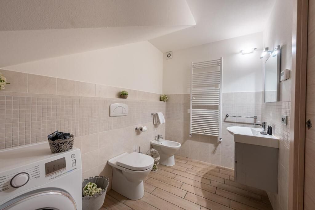 A modern bathroom with a washing machine, toilet, bidet, and a sink.