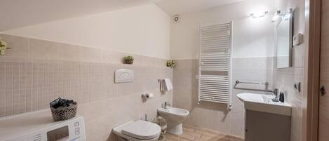 A modern bathroom with a washing machine, toilet, bidet, and a sink.