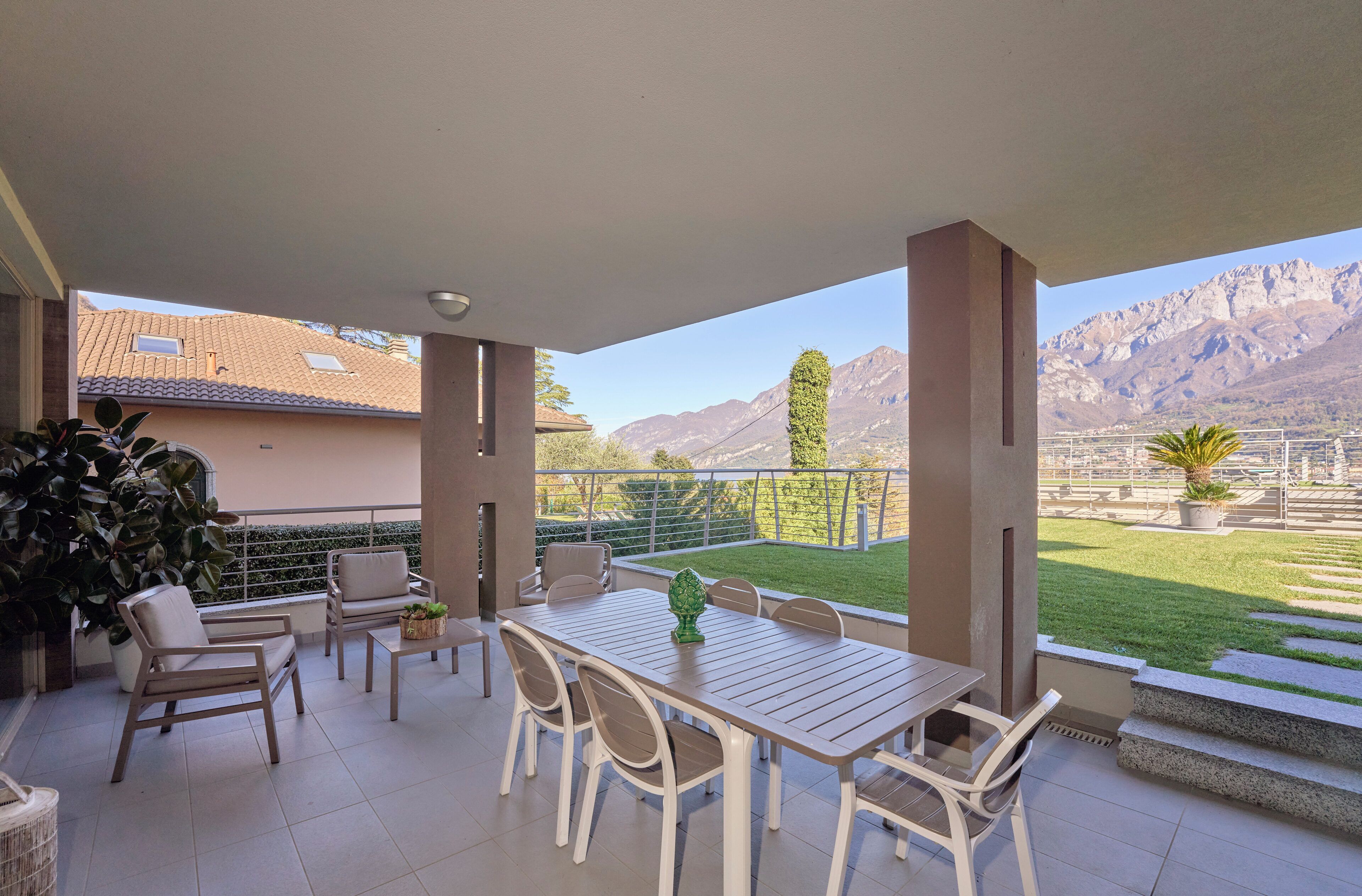 Eine Terrasse im Freien mit Tisch, Stühlen, einer Topfpflanze und Blick auf Berge.