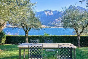 A table with chairs in a grassy area with a view of the sea and mountains. - Bellagio Village (Oliveto Lario)
