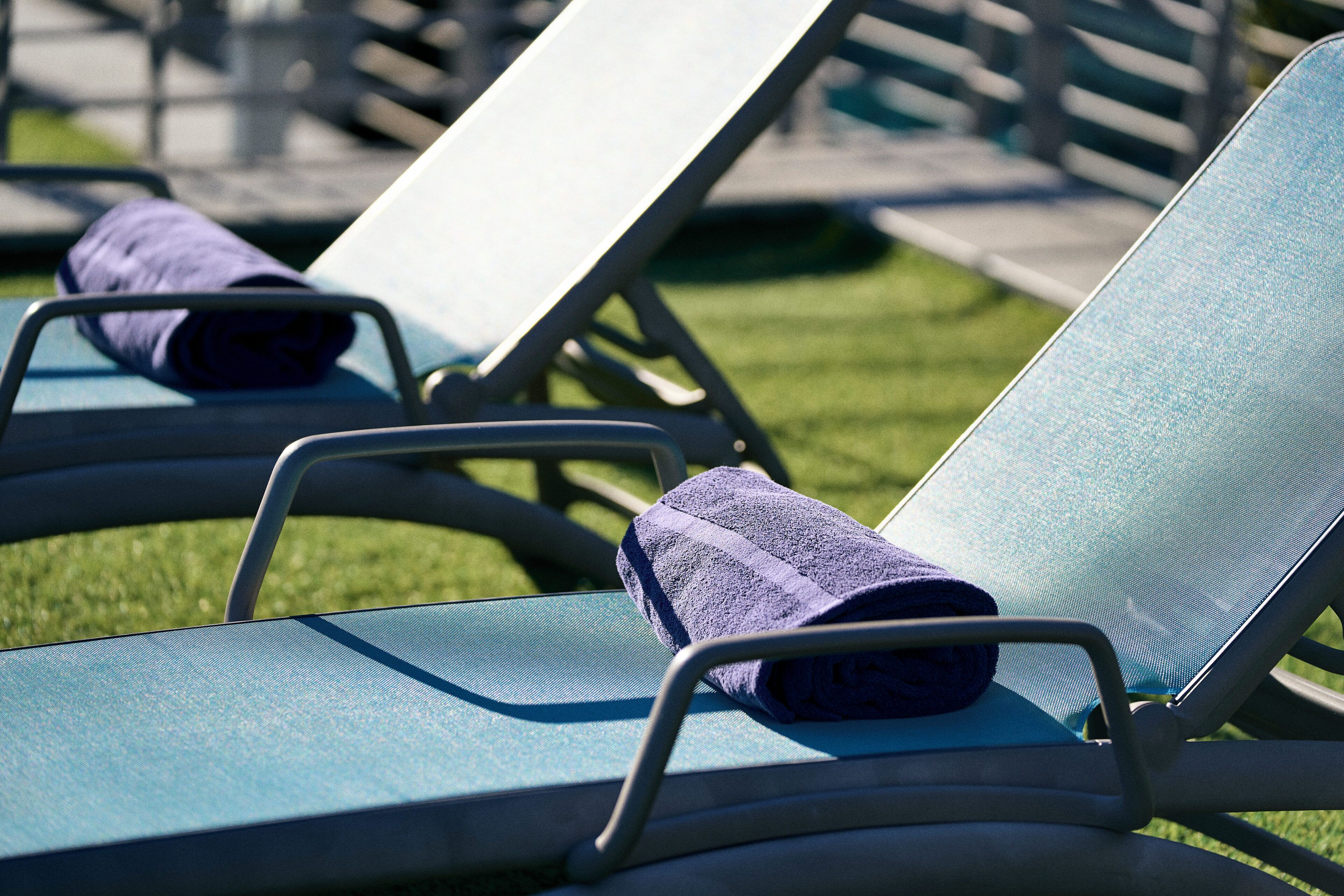 Une rangée de chaises longues avec des serviettes, disposées sur une pelouse.