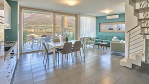 A modern living room with a dining area, a staircase, and a large window offering a mountain view. - Bellagio Village (Oliveto Lario)