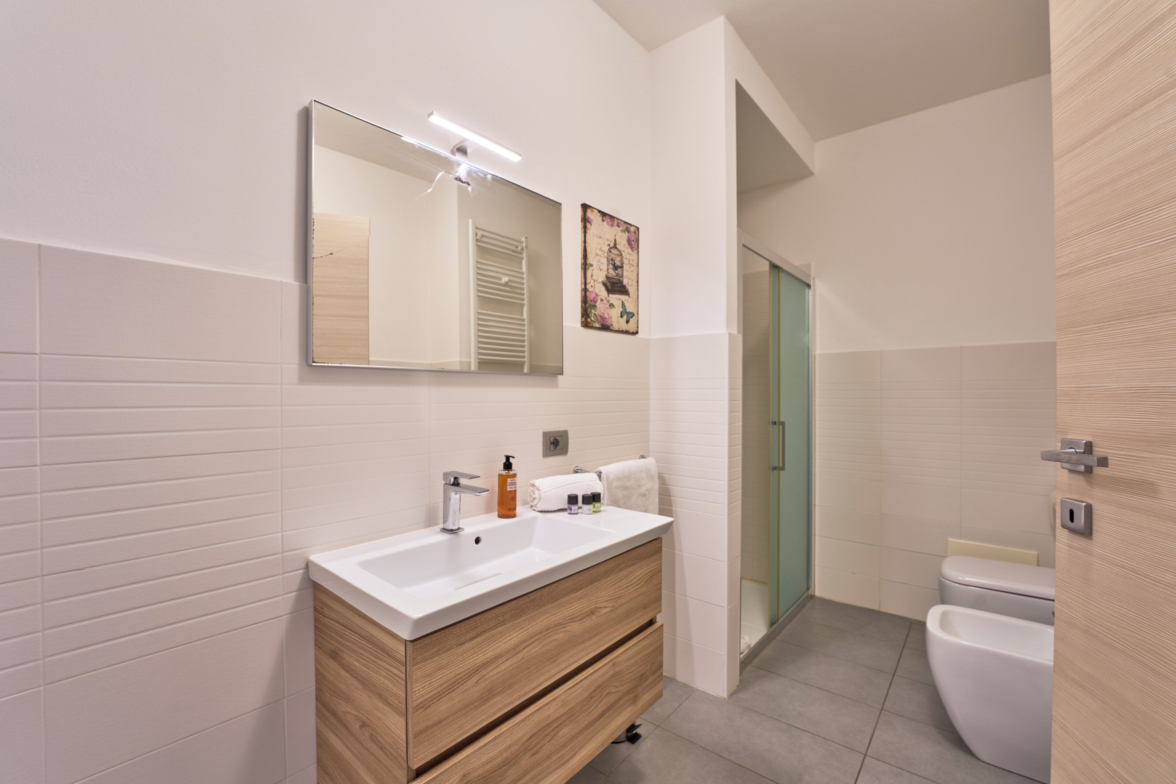 A modern bathroom with a white vanity, a large mirror, and a glass shower enclosure.