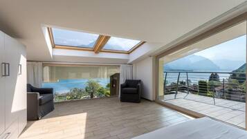 Een moderne slaapkamer met dakraam, groot raam met uitzicht op zee en balkon met stoel.