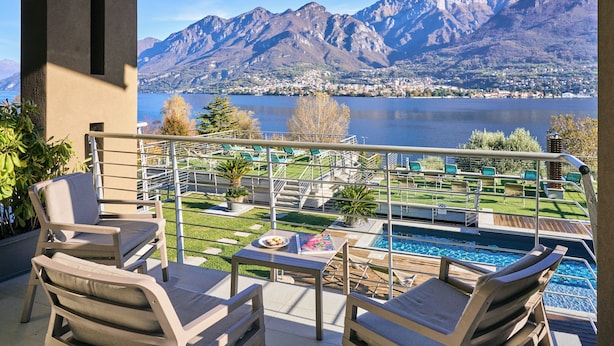 A balcony with outdoor seating, a pool, and a view of mountains and a lake. - Bellagio Village (Oliveto Lario)