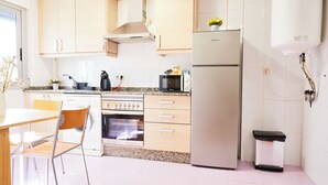 Een moderne keuken met houten kastjes, een roestvrijstalen koelkast, een magnetron en een wasmachine.