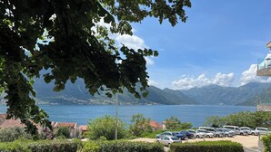 En kustutsikt med en parkeringsplats och byggnader i förgrunden, en klar himmel och berg i bakgrunden.