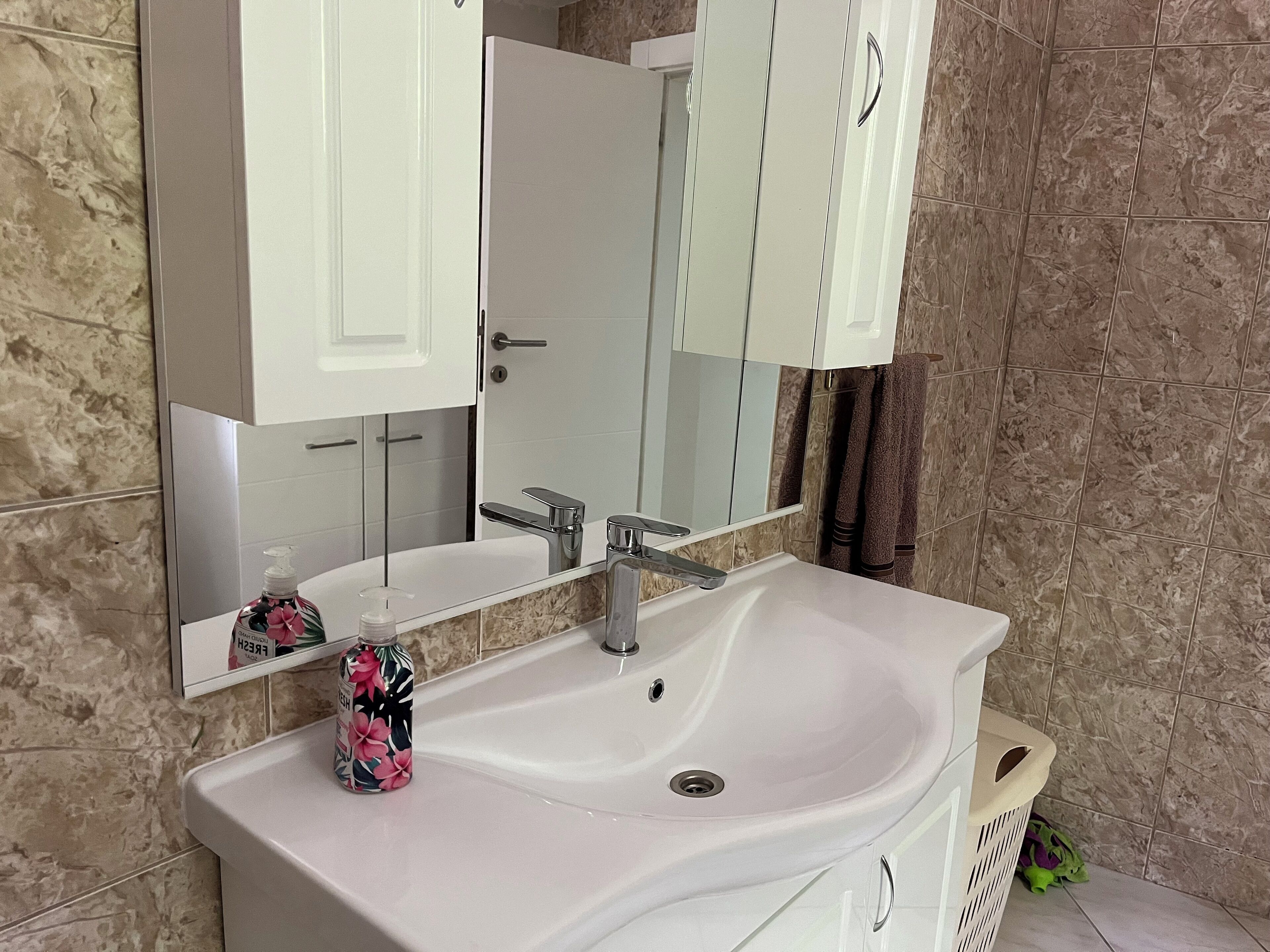 A bathroom with a white sink, a mirror, and a cabinet.