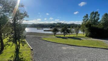 Un’area di parcheggio sterrata con vista su un lago e alberi.