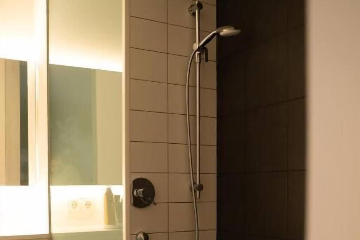 A modern bathroom with a glass shower enclosure, a visible towel rack, and a tiled wall.