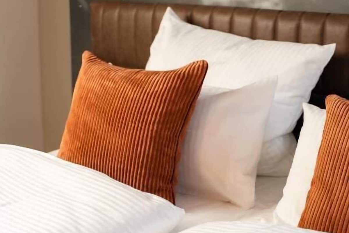 A hotel room with a bed, pillows, and a wall mural.