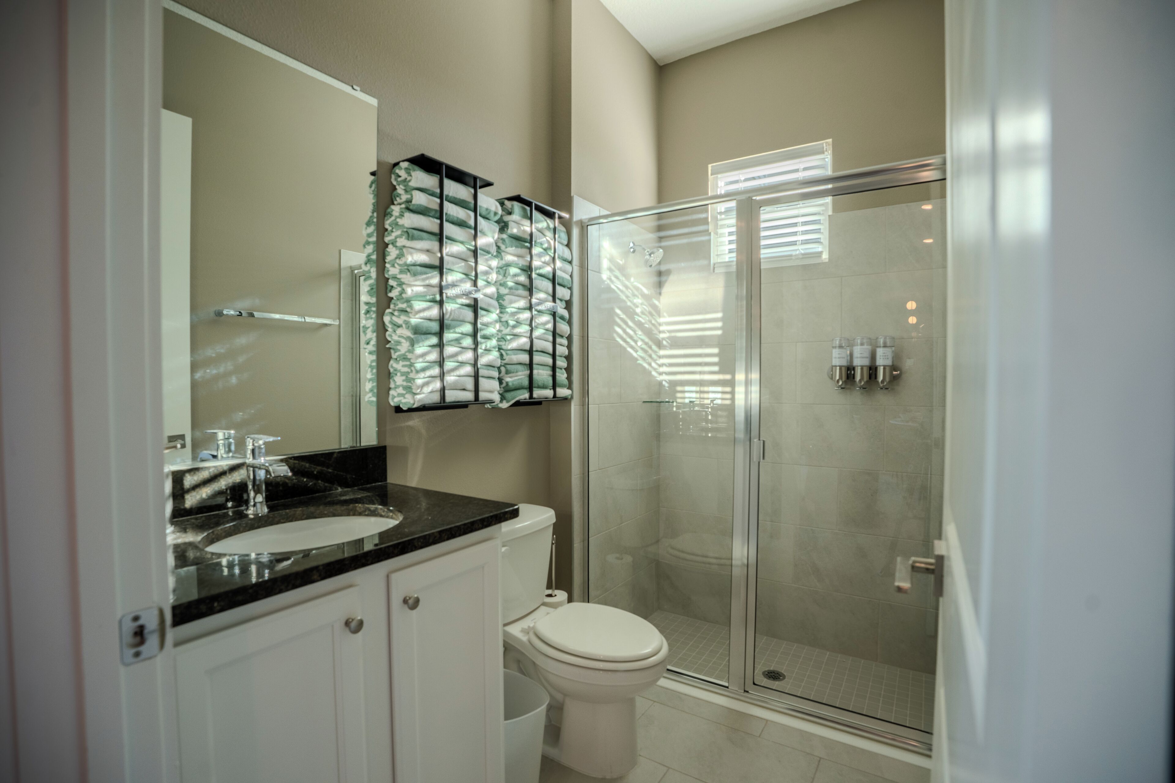 A modern bathroom with a glass-enclosed shower, a white toilet, and a black countertop sink.