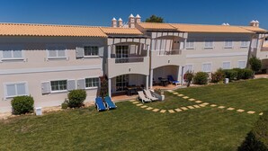 A two-story building with a patio area, outdoor seating, and a well-maintained lawn. - Apartment in Baia Village Condominium with Swimming Pool (Albufeira)