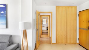 A hallway with a wooden door, a mirror, and a view into a bedroom. - Apartment in Baia Village Condominium with Swimming Pool (Albufeira)