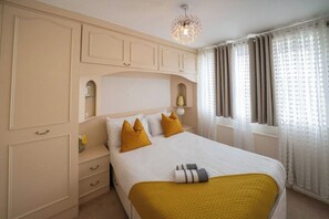 A bedroom with a bed, a nightstand, a dresser, and a window with curtains. - 3-Bed Westhoughton | M61 | Parking (Westhoughton)