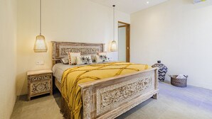 Quarto com uma cama grande, duas mesas de cabeceira e uma cabeceira decorativa.