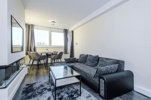 Ein stilvolles Wohnzimmer mit Sofa, Couchtisch und Essbereich mit Stühlen.