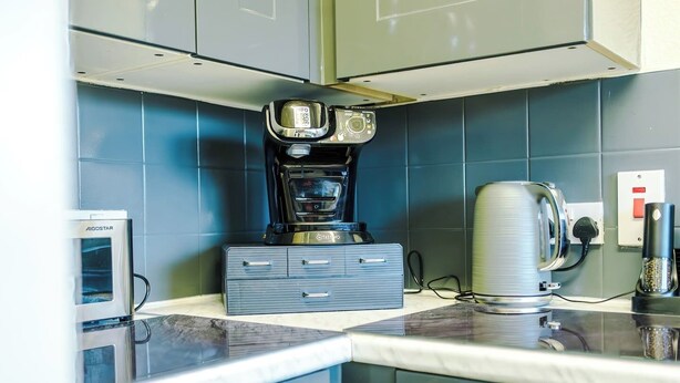 A kitchen with a coffee maker, a kettle, and a microwave. - 1-Bed Flat | Hume | 5 Min to MMU & UoM | 15% Off (Greater Manchester)