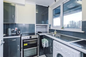 Eine kompakte Küche mit Einbauofen, Waschmaschine und einem Fenster mit Blick nach außen.
