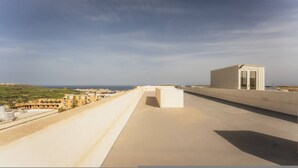 A rooftop terrace with a clear view of the sea and distant buildings. - Gozo Penthouse With Terrace BBQ Private Roof (Xaghra)
