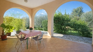 A covered patio with a table and chairs, surrounded by arches and a stone wall. - Apartment With Pool Near Kanegra Beach (Umag)