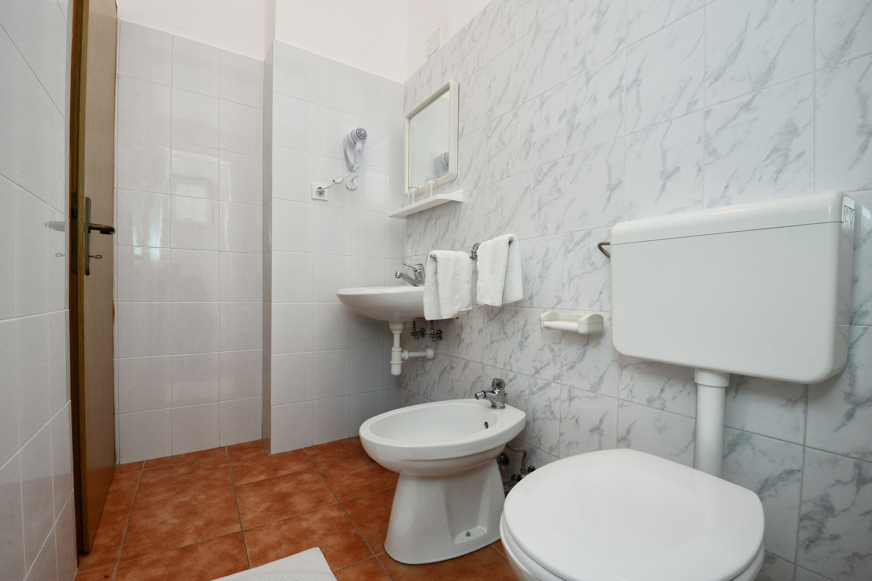 A bathroom with a toilet, bidet, sink, and a mirror.