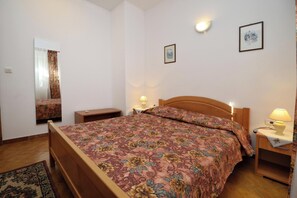 A bedroom with a wooden bed, a nightstand with a lamp, a mirror, and a framed picture on the wall. - Apartment With Pool Near Kanegra Beach (Umag)