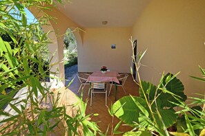 A small patio with a table and chairs, surrounded by plants and a tiled floor. - Apartment With Pool Near Kanegra Beach (Umag)