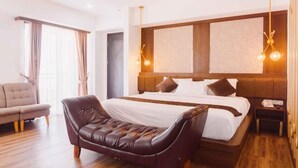 A modern hotel room with a large bed, a leather armchair, a wooden floor, and a view of the city through the window. - Fahira Hotel Bukittinggi Syariah (Bukittinggi)