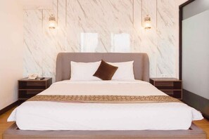 A neatly made bed with a white and brown color scheme, two bedside tables, and a marble-patterned wall. - Fahira Hotel Bukittinggi Syariah (Bukittinggi)