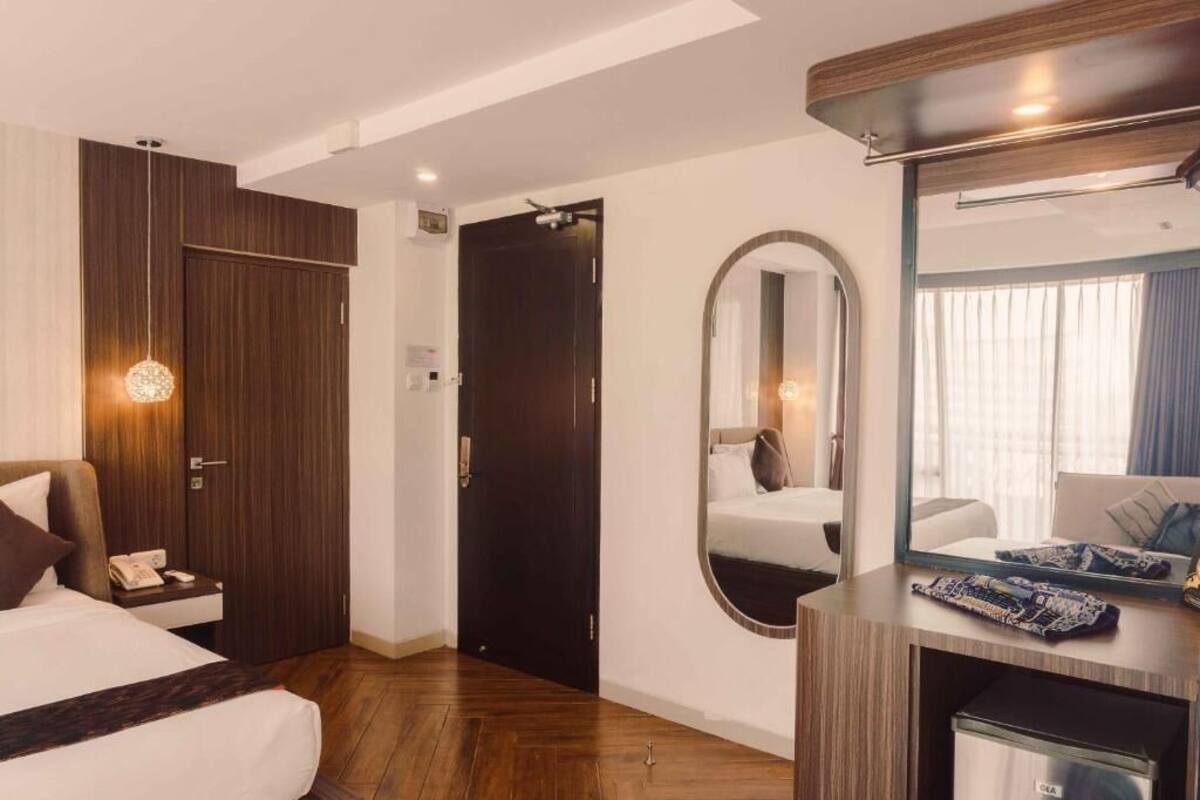 A hotel room with a bed, a desk with a telephone, a mirror, and a wardrobe.
