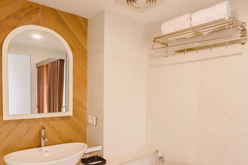 A bathroom with a wooden vanity, a white sink, a mirror, and a towel rack.
