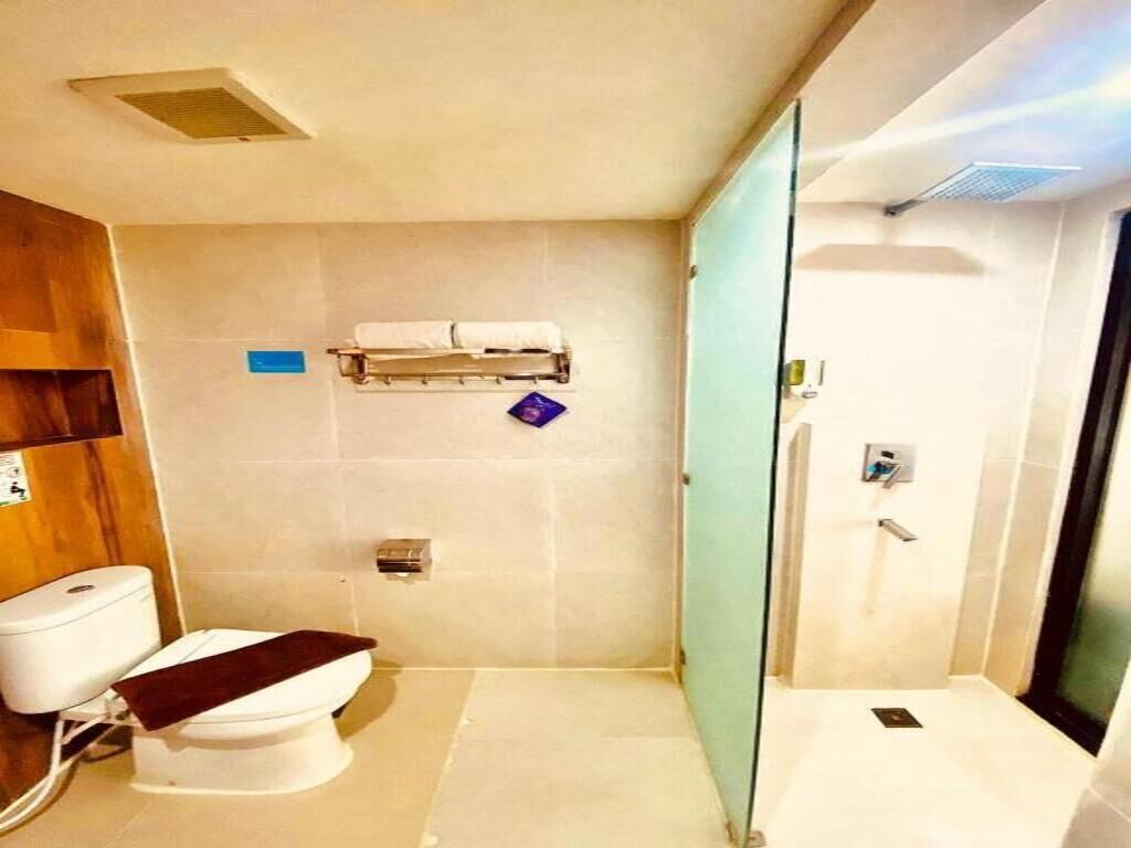 Un baño moderno con inodoro, cabina de ducha de vidrio y toallero.