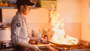 A chef cooking with a large flame on a stove in a kitchen. - Fahira Hotel Bukittinggi Syariah (Bukittinggi)