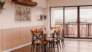 A dining area with a wooden table and chairs, a decorative wall with shells, and a balcony with a view. - Fahira Hotel Bukittinggi Syariah (Bukittinggi)