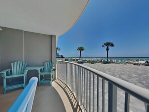 A balcony with a view of the beach, two chairs, and a table. - Tradewinds #002 | Ground-Floor, Gulf-Front, Resort Pool + Snowbird-Friendly (Orange Beach)