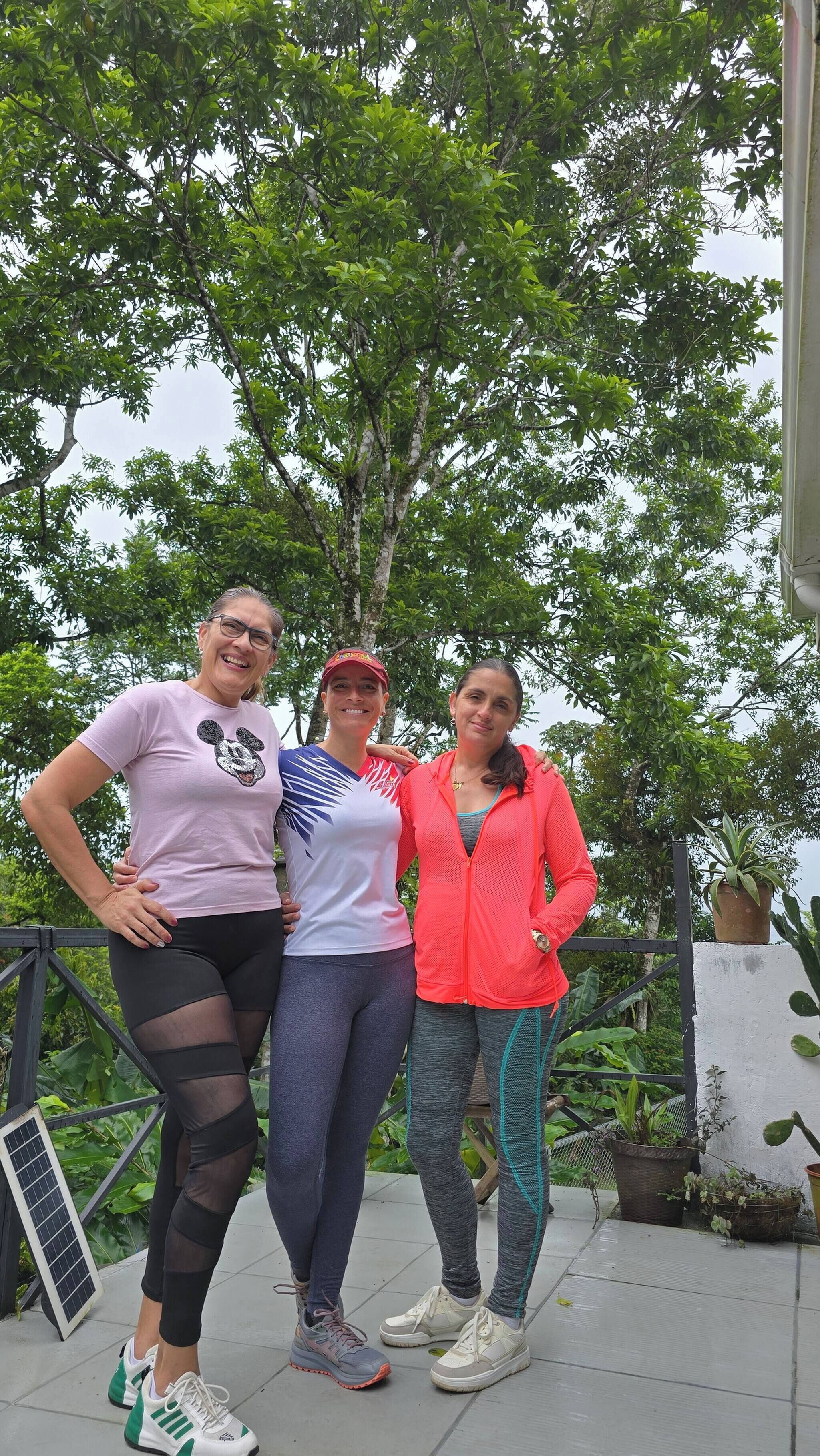 Three people standing outdoors with trees in the background.