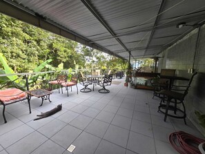 An outdoor patio area with tiled flooring, metal-framed tables and chairs, and potted plants. - Stay at Alexas Nature House (Arenal)
