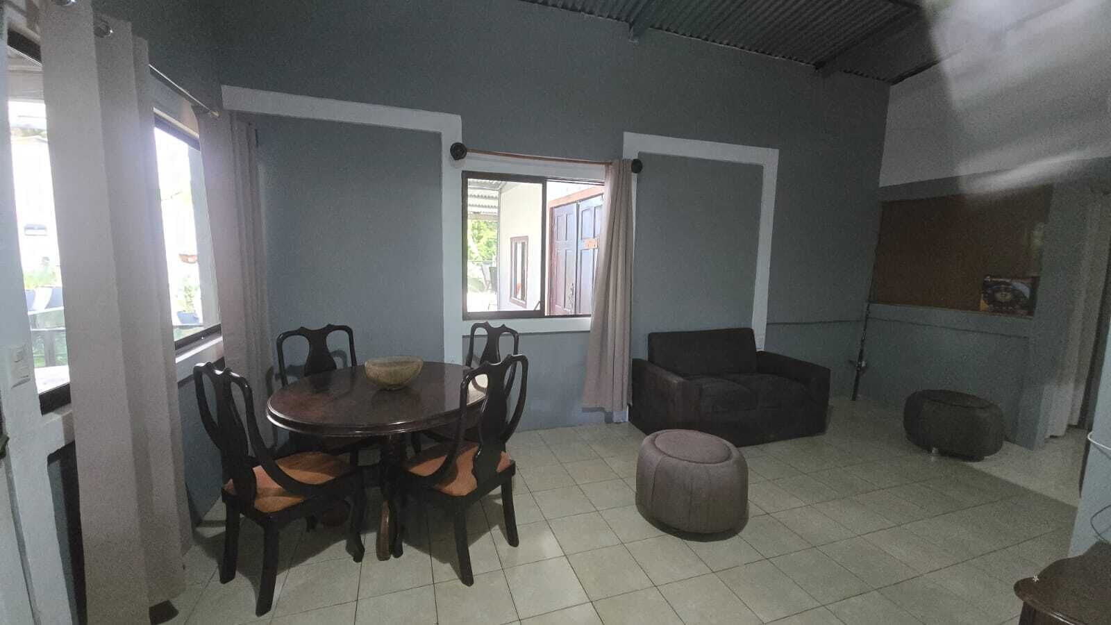 A dining area with a round table and chairs, a sofa, and a small ottoman.