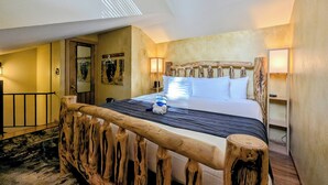 Ein Schlafzimmer mit Holz-Kopfteil, einem Bett mit weißer Bettwäsche, zwei Nachttischlampen und Holzboden.