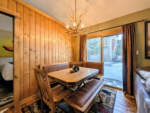 Un intérieur en bois avec une table à manger, des bancs et un lustre.