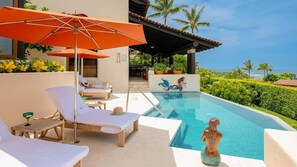 Un espace aménagé au bord de la piscine, avec des chaises longues, un parasol et une statue.