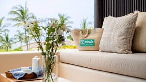 Un canapé avec un sac en tissu tissé et un coussin à motifs, un vase avec des fleurs et un plateau avec une théière et des tasses.