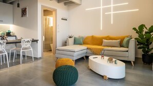 Una sala moderna con un sofá modular, una mesa de centro blanca y una lámpara de pared con forma de cruz.