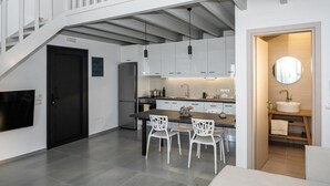 Una cocina moderna con armarios blancos, una isla central con sillas, horno empotrado y un ventanal grande.