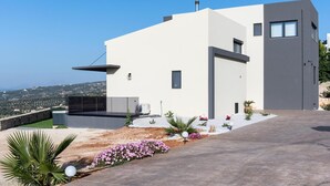 Una casa moderna de dos pisos con techo plano, un balcón grande y vistas al campo.