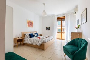 A bedroom with a bed, bedside tables, a green armchair, and a window with curtains. - Spacious and bright, just a few steps from the Colosseum and the subway (Roma)