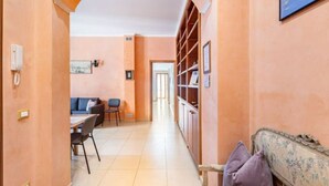 A hallway with a sofa, dining table, chairs, and a bookshelf. - Wide and Bright, only a few steps from Colosseum & metro (Roma)