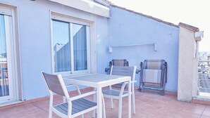 Un balcón con mesa y sillas, una ventana y vistas de la ciudad.